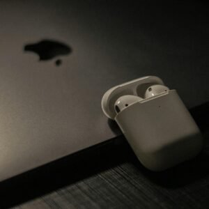 Sleek wireless earbuds in a case resting on a laptop surface, showcasing modern technology.